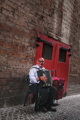 musical instrument man sitting on black chair holding accordion person